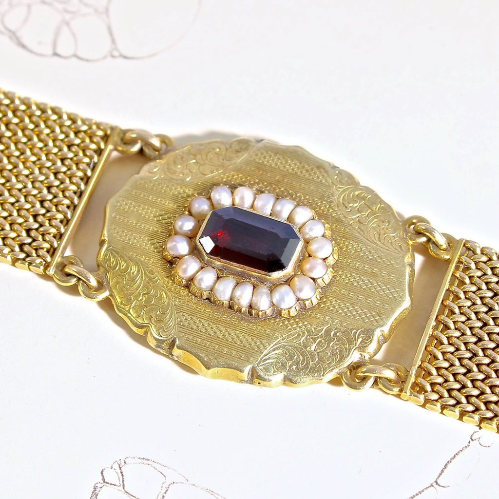 Wide antique yellow gold mesh chain bracelet with a garnet center stone that has a pearl halo.