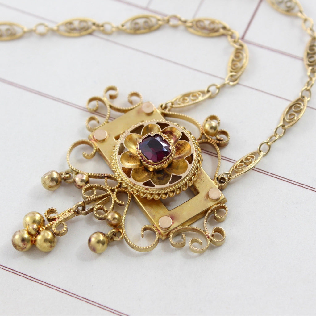 Antique 14k yellow gold filigree pendant necklace with a cushion cut garnet and tiny gold balls.