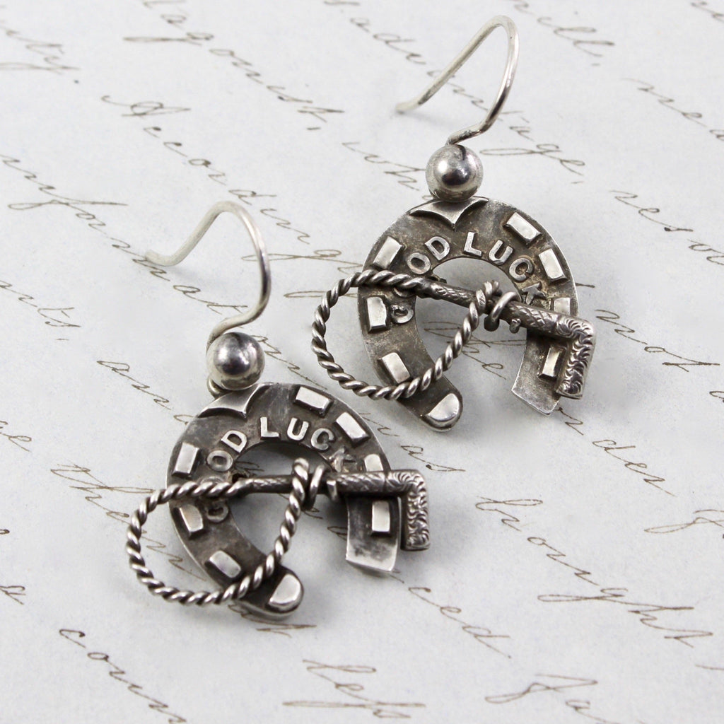 Antique sterling silver hook earrings with with horseshoe charms that read &quot;Good Luck&quot;.